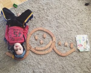 boy made happy face out of toy train tracks