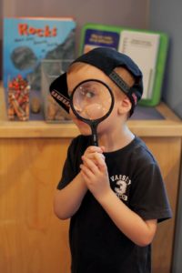 boy holding magnifying glass over eye