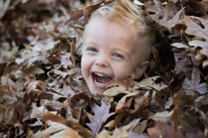 young boy totally covered up by leaves